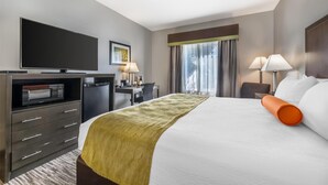 A hotel room with a large bed, a flat-screen TV, a desk with a lamp, a microwave, and a coffee maker. - Best Western Plus Liberal Hotel & Suites (Liberal)