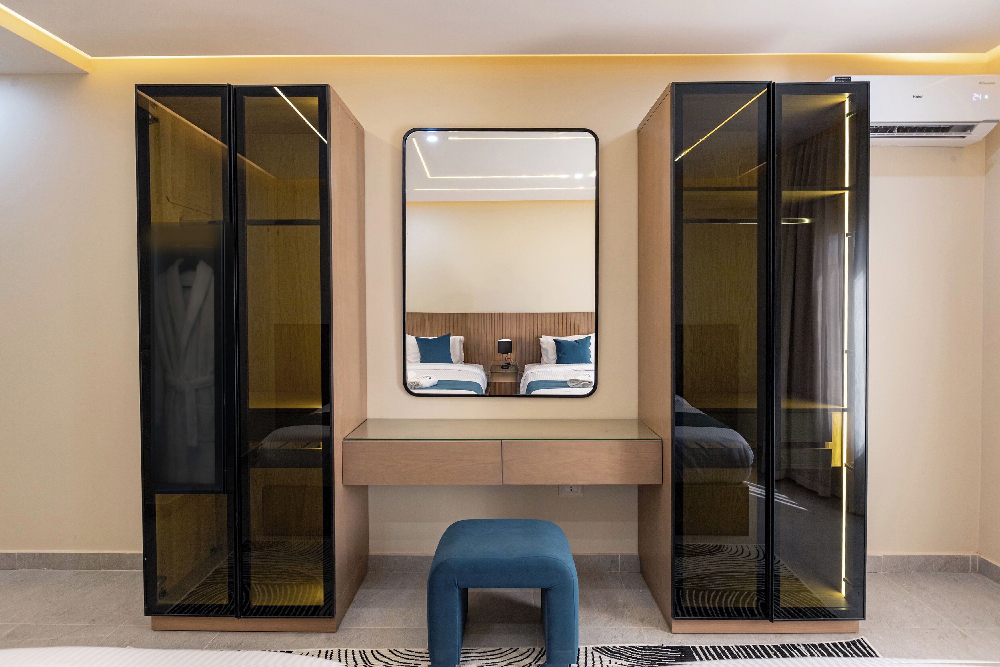 Une chambre moderne dotée d’une armoire intégrée, d’un miroir au-dessus d’une coiffeuse et d’un banc.