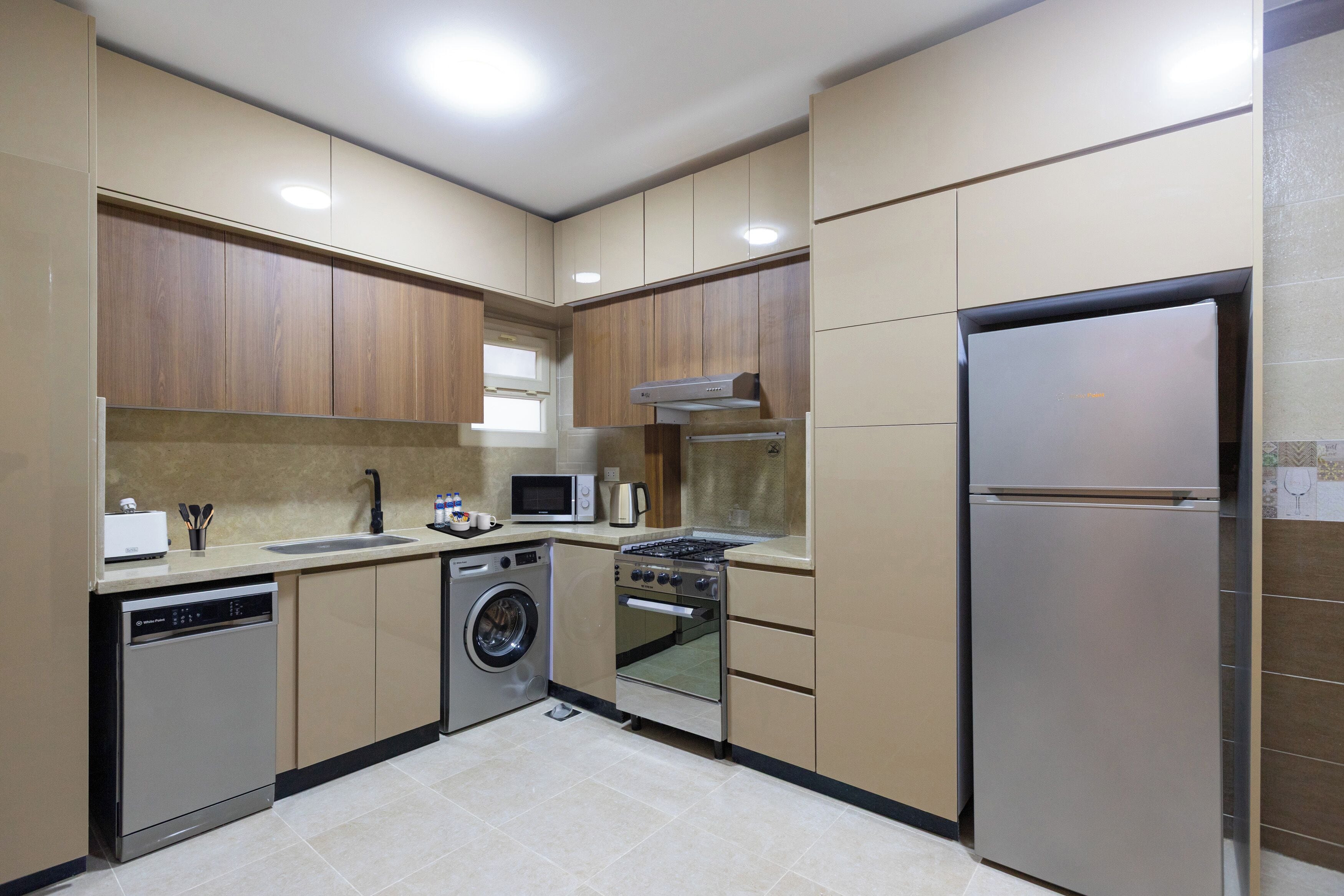 A modern kitchen with built-in appliances, including a dishwasher, washing machine, oven, and refrigerator.