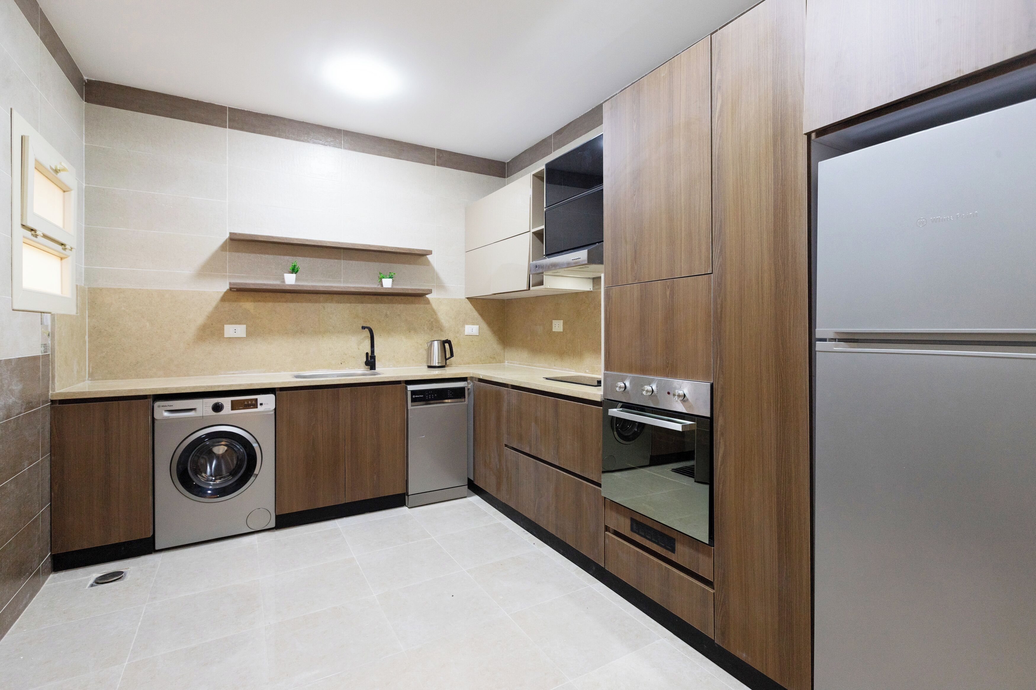 A modern kitchen with built-in appliances, including a dishwasher, washing machine, oven, and a refrigerator.