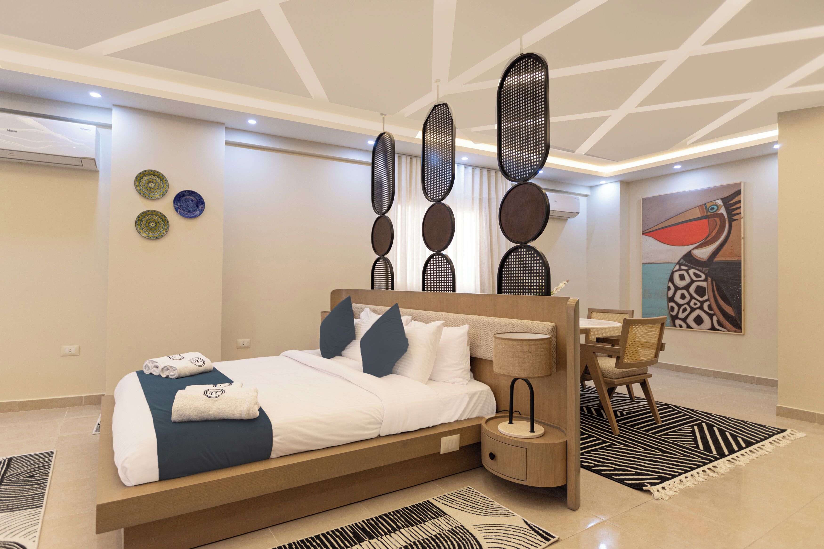 Een moderne hotelkamer met een groot bed, een houten nachtkastje, een zithoek en decoratieve wandkunst.