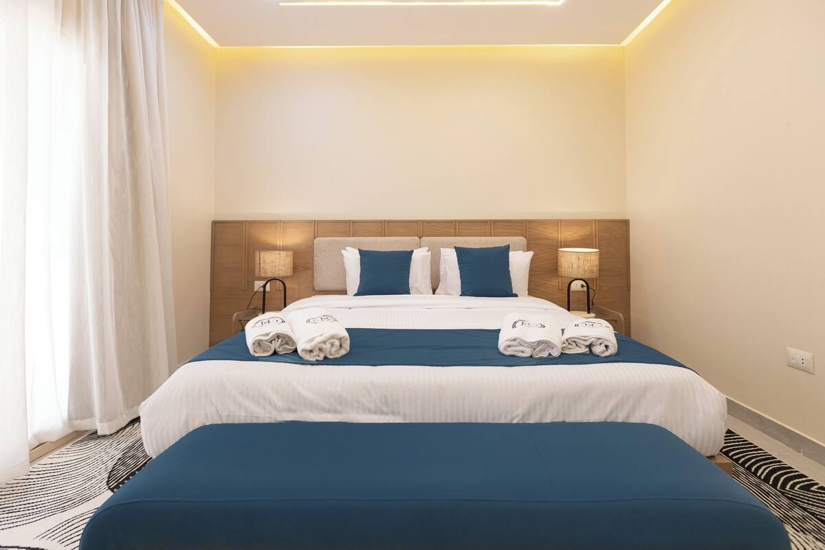 Ein Hotelzimmer mit einem großen Bett, zwei Nachttischen, einer Kopfteil und einem Vorhangfenster.