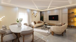 Ein modernes Wohnzimmer mit einem runden Esstisch, Sofas und einem flachbildfernseher an der Wand.