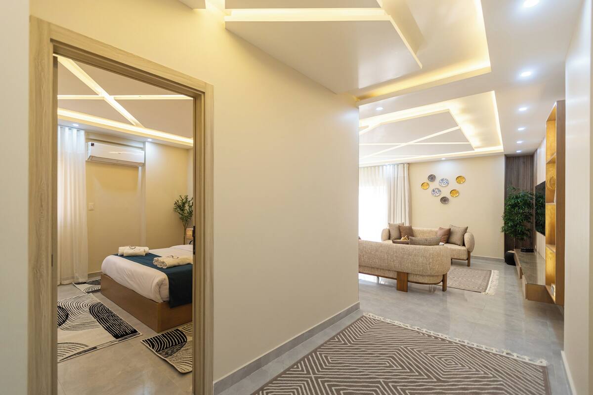 Ein modernes Hotelzimmer mit Bett, Sofa, Couchtisch und einem an der Wand befestigten Fernseher.