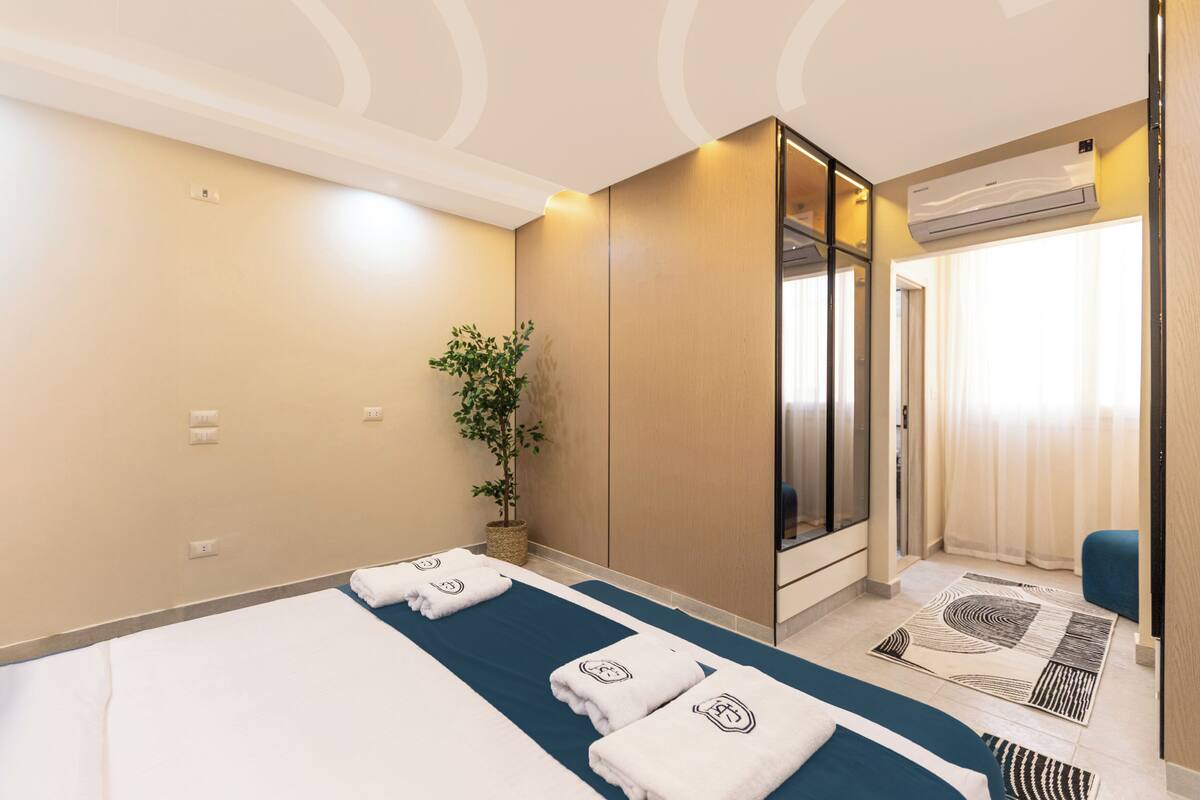Ein Hotelzimmer mit Bett, Topfpflanze, Spiegel und Klimaanlage.