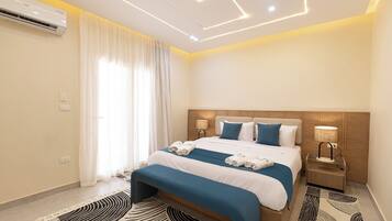 A modern hotel room with a neatly made bed, a bedside table with a lamp, and a large window with curtains.