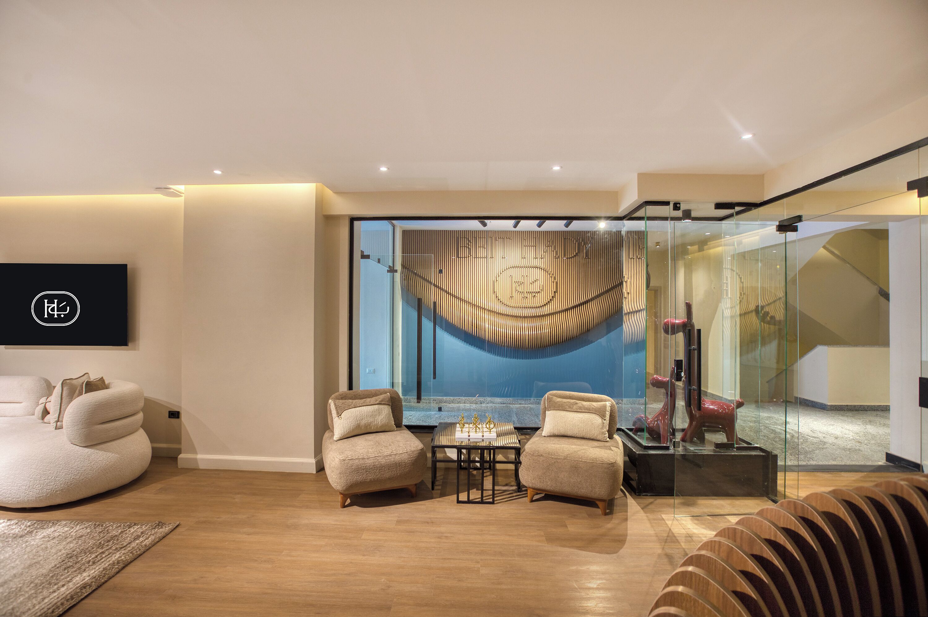 Un salón moderno con un ventanal grande, dos sillones, una mesita y un sofá.