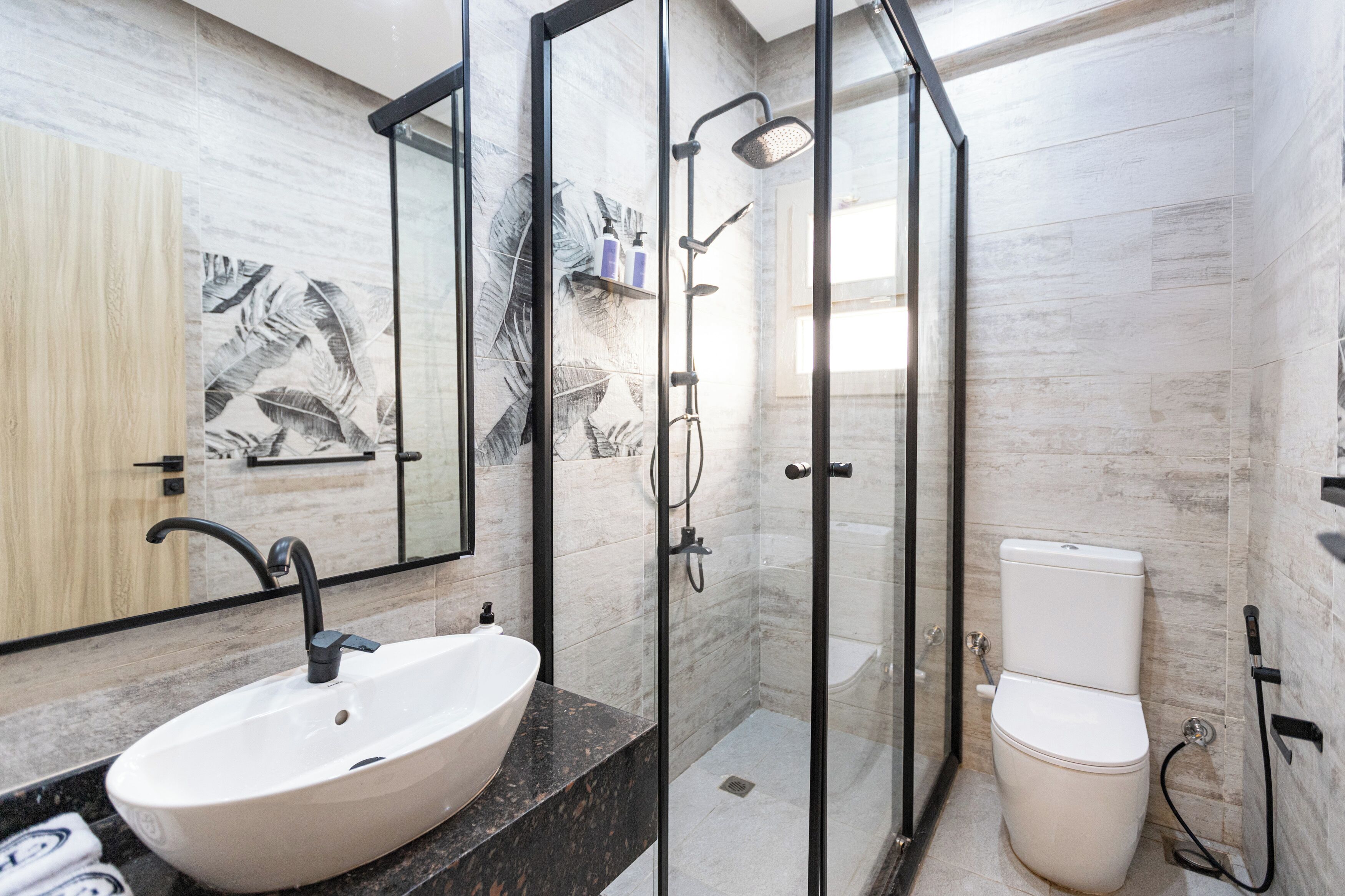 A bathroom with a large white sink, a glass-enclosed shower, and a toilet.
