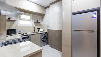 Eine moderne Küche mit einem Edelstahl-Kühlschrank, einem eingebauten Backofen, einer Mikrowelle, einer Waschmaschine und einem Gasherd.