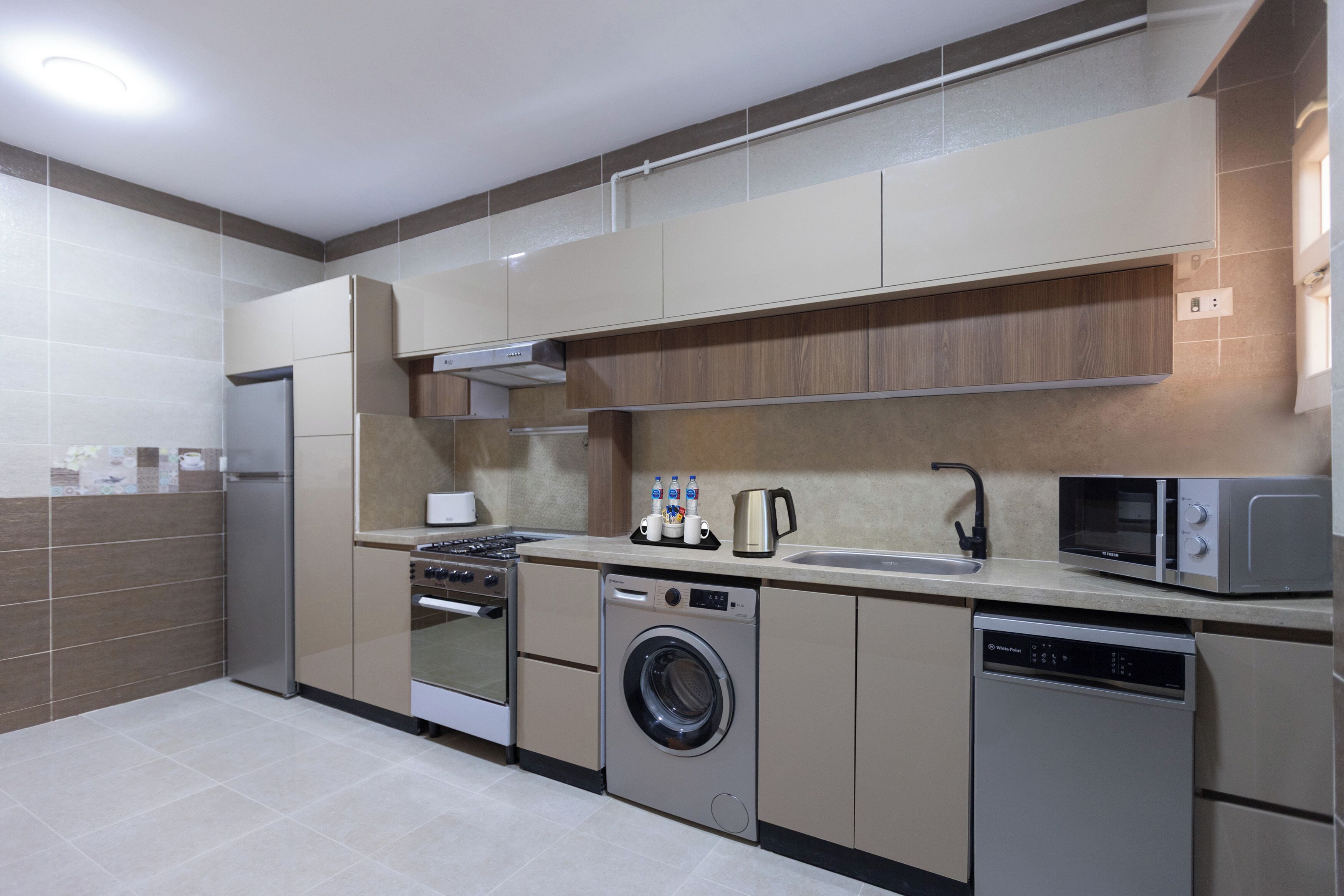 A modern kitchen with a built-in washing machine, dishwasher, microwave, and oven.
