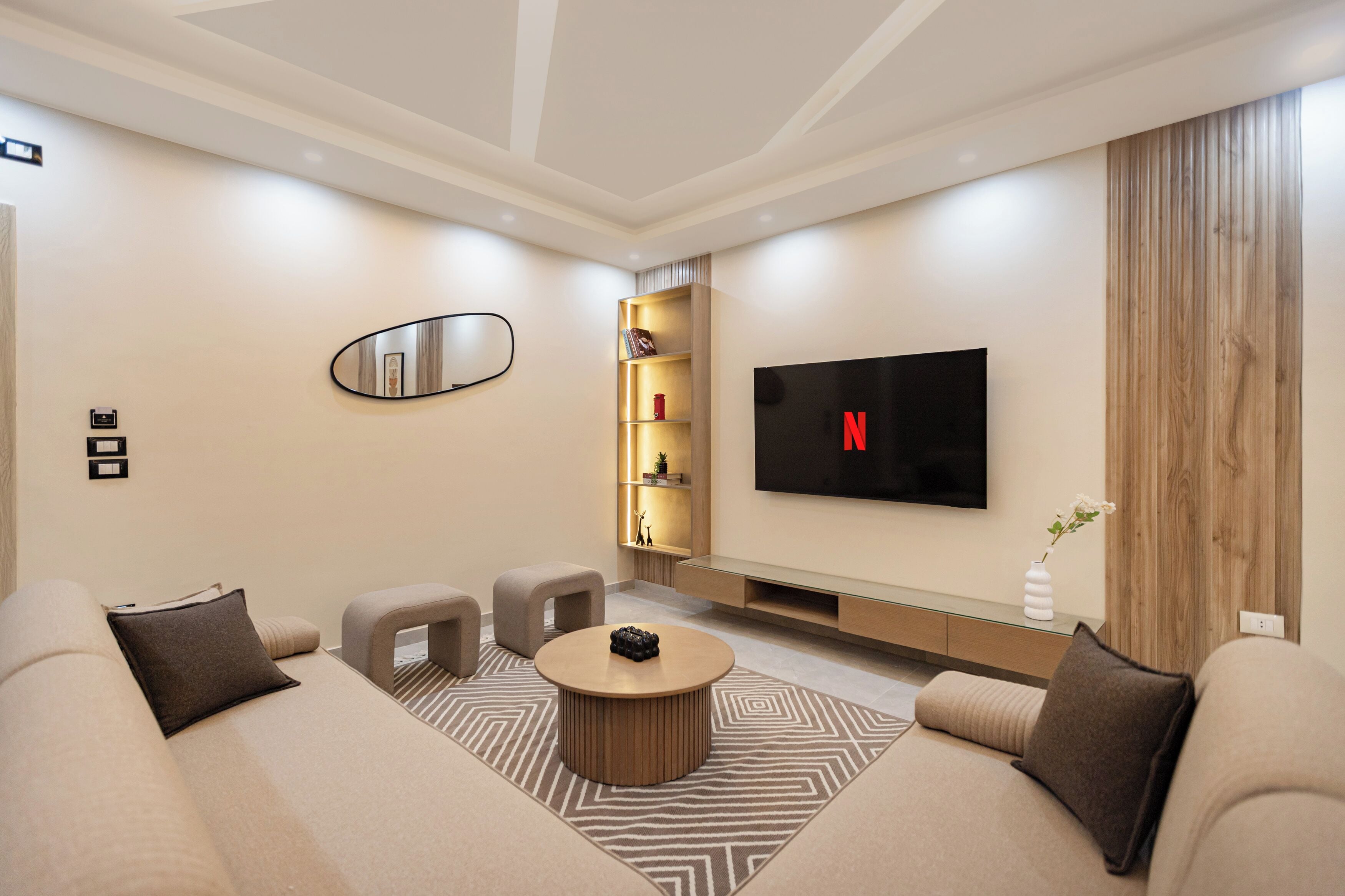 A modern living room with a sofa, coffee table, and a flat-screen TV mounted on the wall.