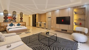 Ein modernes Wohnzimmer mit Sofa, Couchtisch, Fernseher und Küchenzeile.