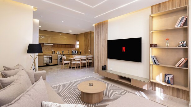 Ein modernes Wohnzimmer mit einem Flachbildfernseher, einem Sofa, einem Couchtisch und einem Bücherregal.