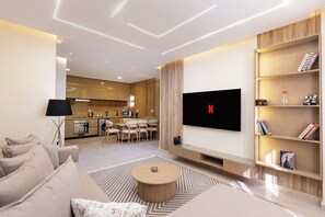 Un salon moderne avec un téléviseur à écran plat, un canapé, une table basse et une bibliothèque.