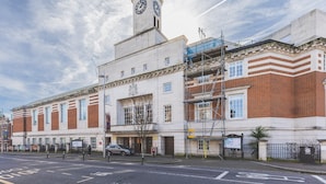 A historic building with a clock tower, brick facade, and scaffolding. - Stylish Historic Acton Apartment (London)