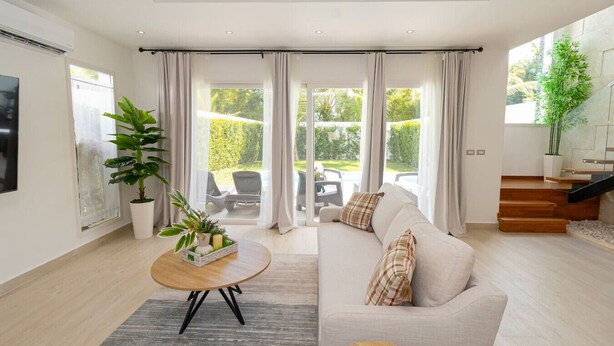 Un salon moderne avec un canapé, une table basse et un escalier menant à un espace extérieur.