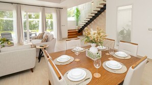 Un espace repas moderne avec une table en bois dressée pour six personnes, entourée de chaises blanches.