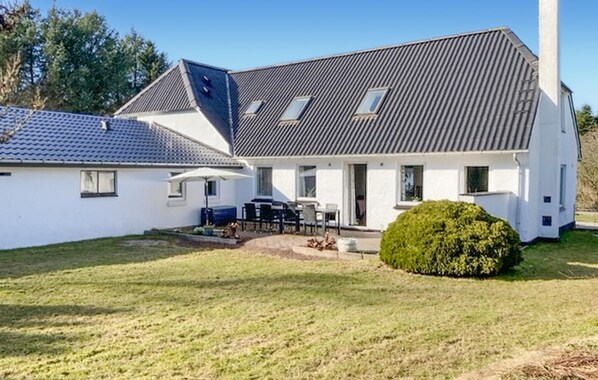Uma casa de dois andares com telhado inclinado, varanda coberta e gramado bem cuidado.