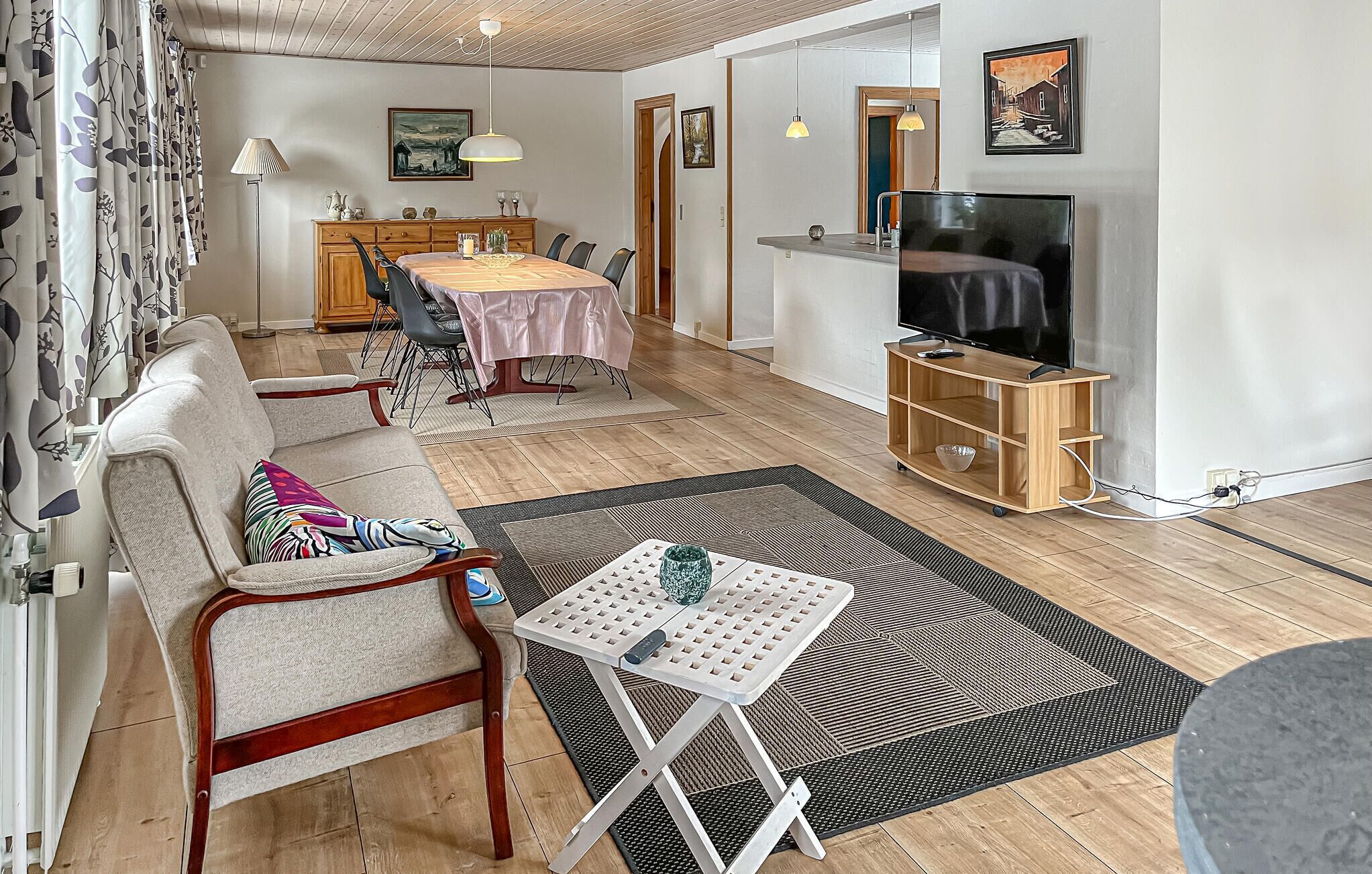 Uma sala de estar moderna com sofá, mesa de jantar e aparador para TV.