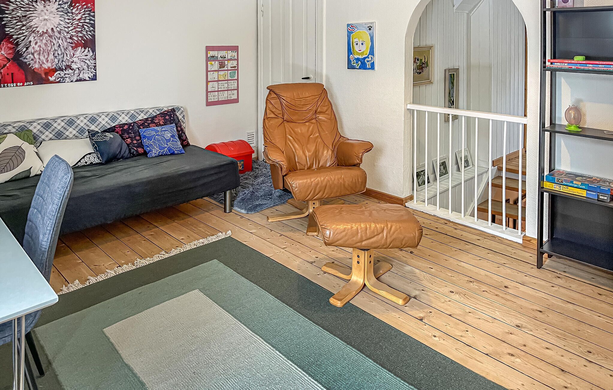 A living room with a sofa, a brown leather chair, a small table, and a bookshelf.