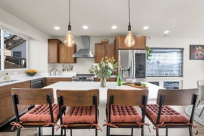 Une cuisine moderne avec des meubles en bois, un îlot central et des luminaires suspendus.
