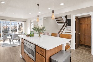 Une cuisine moderne dotée d’un grand îlot central, de meubles en bois et de luminaires suspendus.