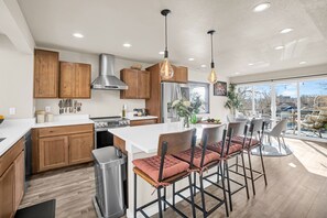 Una cocina moderna con armarios de madera, electrodomésticos de acero inoxidable y una isla central con taburetes de bar.