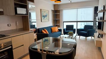 A modern kitchen with built-in appliances, a dining area with a glass table, and a living space with a sofa and armchairs.