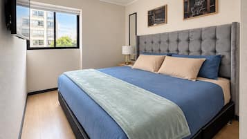 Ein Schlafzimmer mit einem großen Bett, einem Fenster und einem am Wand montierten Fernseher.
