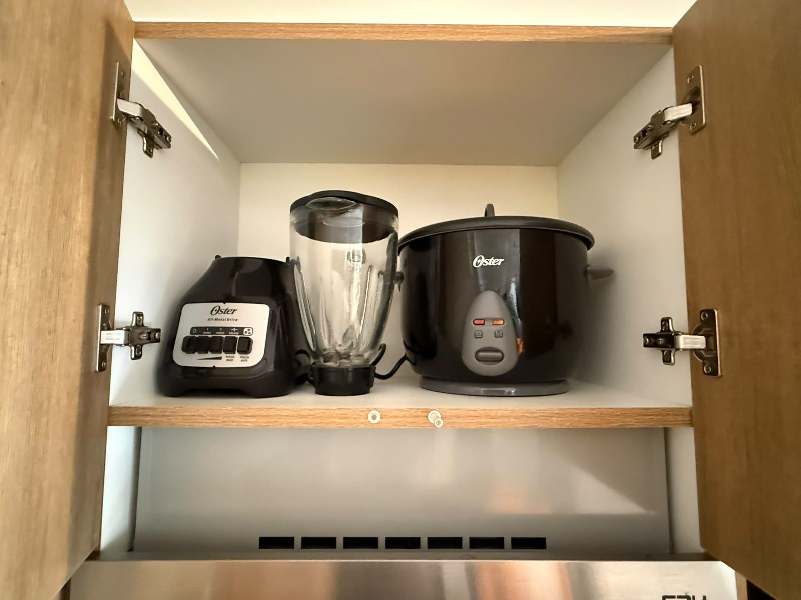 A kitchen cabinet with a blender and a slow cooker.