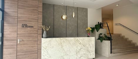 A reception area with a marble counter, wooden cabinets, and a staircase.