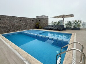 A rooftop swimming pool with tiled steps, lounge chairs, and an umbrella. - APT STYLE - MAGDALENA (Lima)