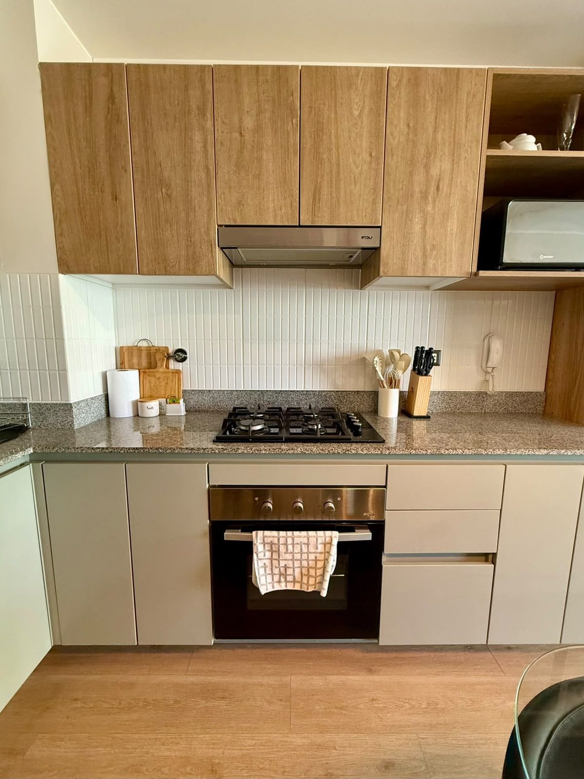 Una cocina moderna con armarios de madera, una campana extractora de acero inoxidable y un horno empotrado.