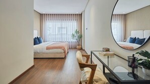 Een hotelkamer met een bed, een bureau, een stoel, een spiegel en een raam met gordijnen.