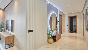 Een moderne hotellobby met een houten receptiebalie, een grote spiegel en een potplant.