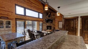 A rustic interior with a stone bar, wooden walls, a fireplace, and a 'Gather' sign.