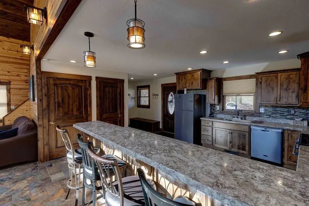 A kitchen with a granite countertop, wooden cabinets, and a refrigerator.