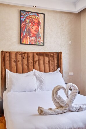 Een hotelkamer met een groot bed, witte beddengoed, een houten hoofdeinde en een kleurrijk schilderij aan de muur.