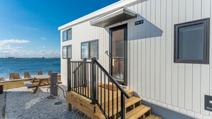 A modern building with a wooden deck, a staircase, and a view of the sea. - Direct Waterfront Cabin Sunset Views 3 (Fort Walton Beach)