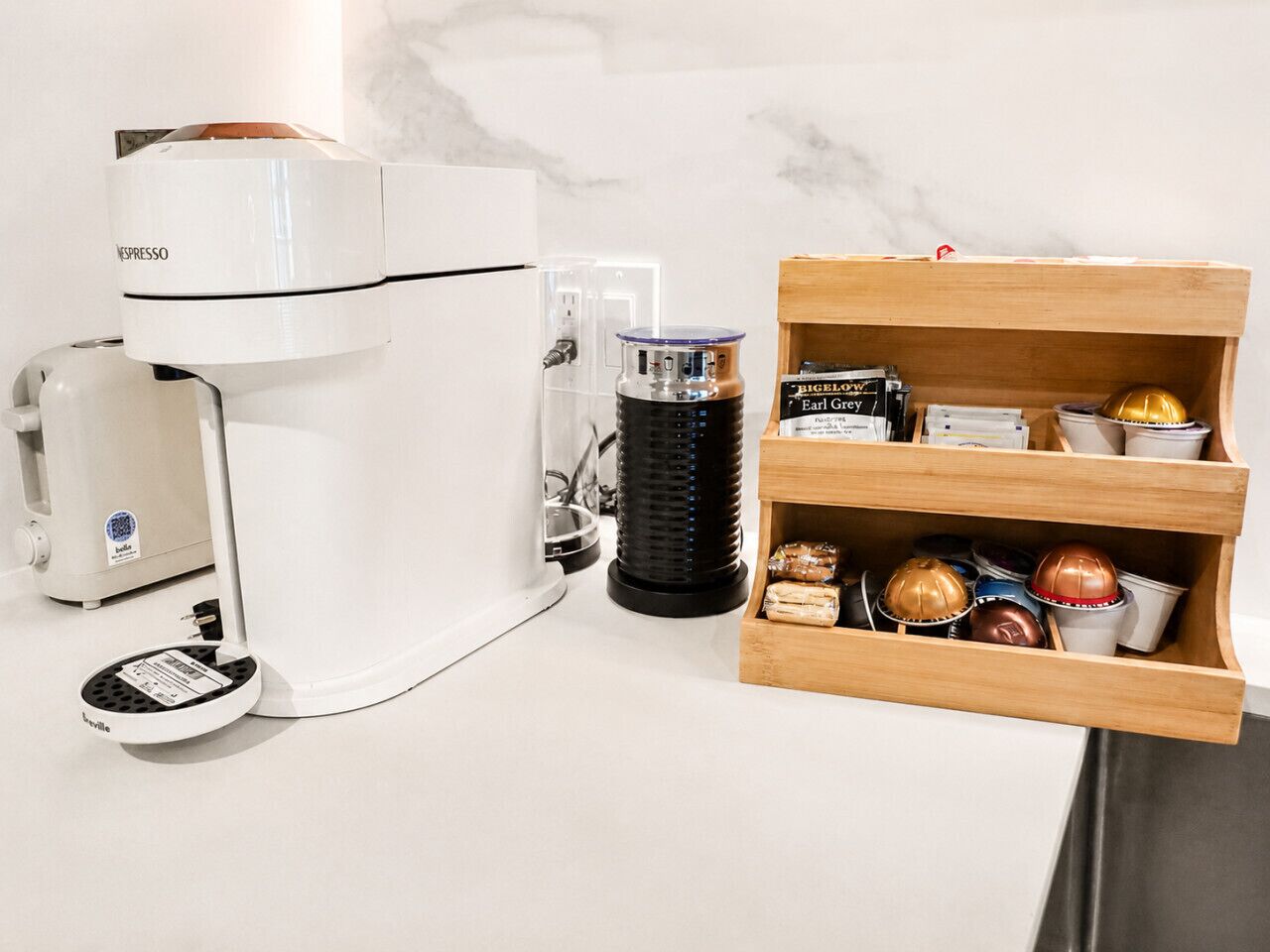 A coffee machine, a coffee grinder, and a wooden storage unit with coffee pods and a coffee grinder.