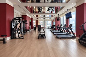 Ein Fitnessstudio mit Laufbändern, Krafttrainingsgeräten und Blick auf die Stadt.