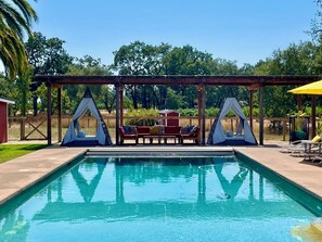 A swimming pool with two gazebos, a red sofa, and a yellow umbrella. - 4Bd Wine Country Vineyard Retreat + Pool + Hot Tub, a perfect relaxing getaway! (Santa Rosa)