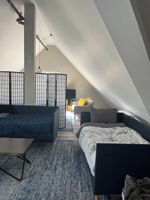 Een slaapkamer met een bed, een bureau en een stoel. Er is een scheidingswand met een rasterpatroon.