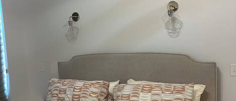 Een slaapkamer met een bed, twee wandlampen en een nachtkastje.