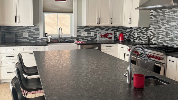 A modern kitchen with white cabinets, a granite countertop, and red pendant lights. - Steps from Old Port. New, Beautifully Appointed Home. Sleeps up to 11. (Portland)