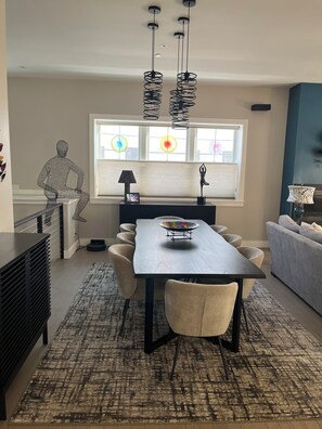 Een moderne eetruimte met een donker houten tafel, beige stoelen en een kamerkleed met een patroon.