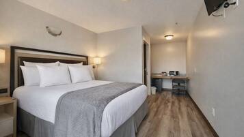 Una habitación de hotel con cama, mesita de noche, escritorio y televisión.