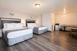 A hotel room with two beds, a desk, a chair, a microwave, and a trash bin. - Siesta Inn (Salt Lake City)