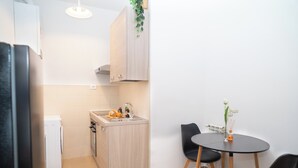 Une cuisine de taille réduite comprenant un évier, une petite table à manger avec des chaises et un réfrigérateur.