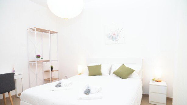 Une chambre d’hôtel bien rangée, avec un lit, des tables de chevet, un bureau et une chaise.
